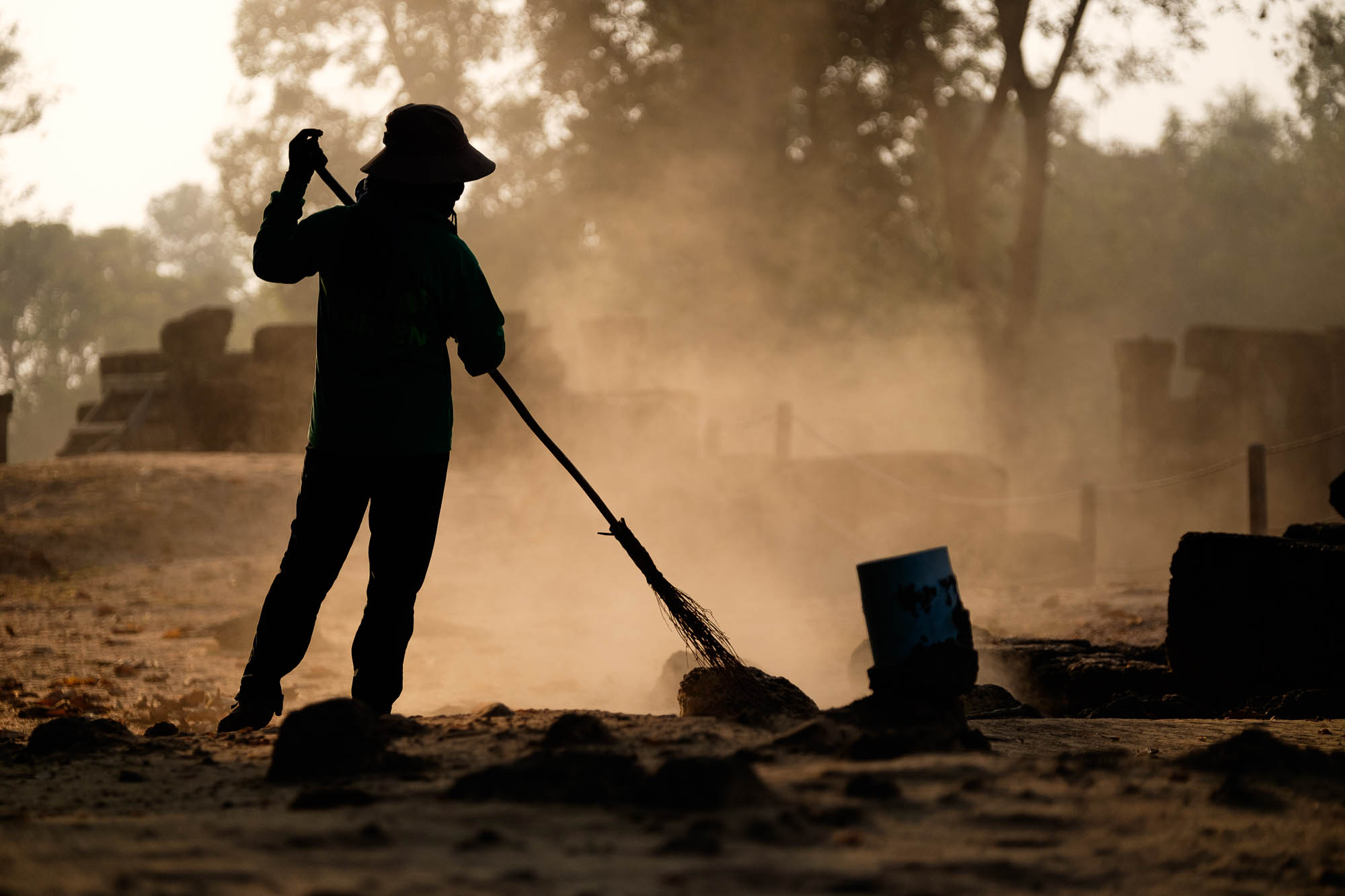 Women with broom in dust  - Cambodia